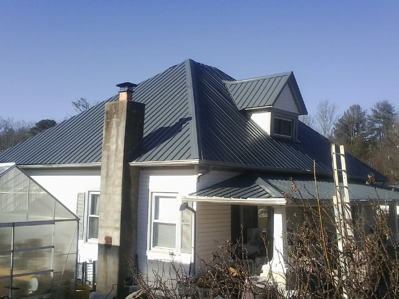Dark blue standing seam metal roof on a white farmhouse with dormer — Slate & Tile Roof Repair by Roofing Brothers in San Lorenzo