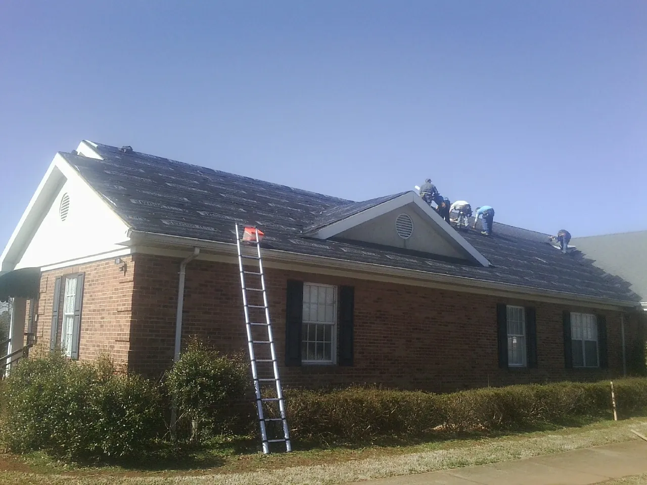 Crew tearing shingles off a brick ranch roof with a ladder set — Metal Roof Repair work by our crew in San Lorenzo