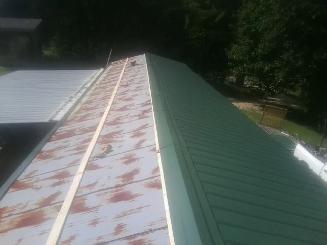 Old rusted panels beside newly installed green metal roofing — Wind Damage Roof Repair by Roofing Brothers in San Lorenzo