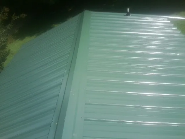 New green metal panels meeting at the ridge of a roof — Flat Roof Repair work by our crew in San Lorenzo