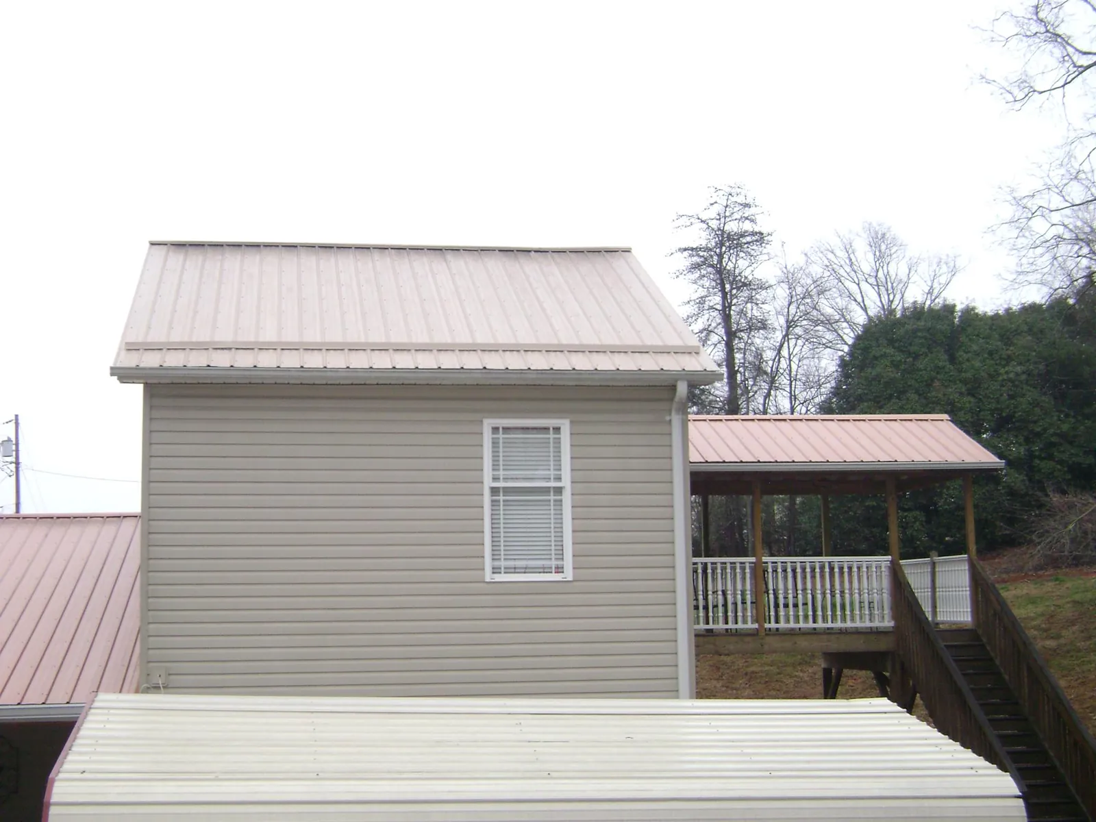 Tan metal roofs on a two story addition and attached porch, from a Roof Replacement job in San Lorenzo