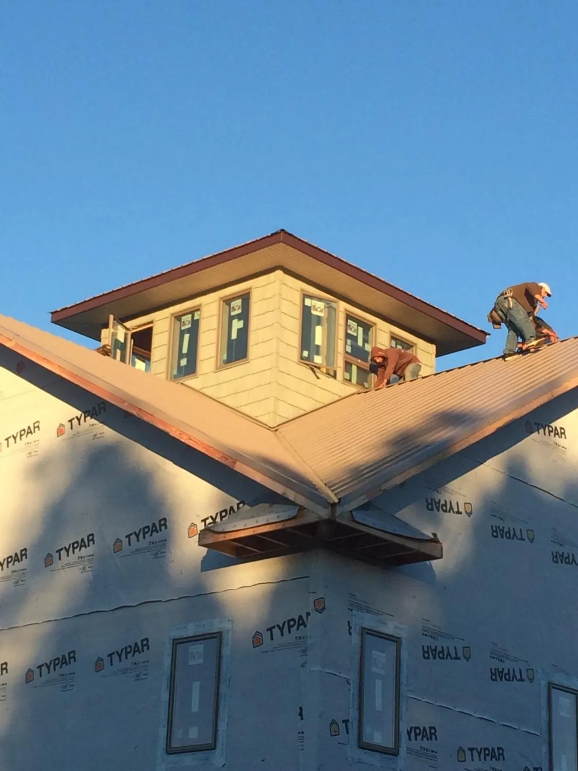 Roofers working around a rooftop cupola on a new metal roof at sunset — Roof Waterproofing in San Lorenzo by Roofing Brothers